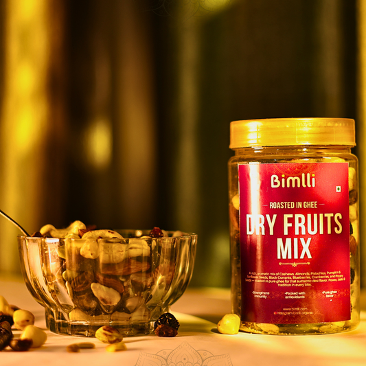 Jar of Bimlli Dry Fruits Mix with a bowl of mixed nuts on a blurred background
