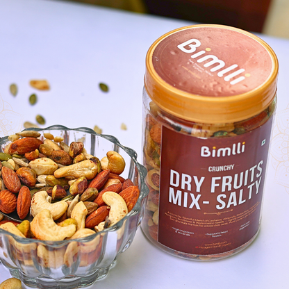 Bimlli Crunchy Dry Fruits Mix Salty jar with a bowl of assorted nuts on a white surface