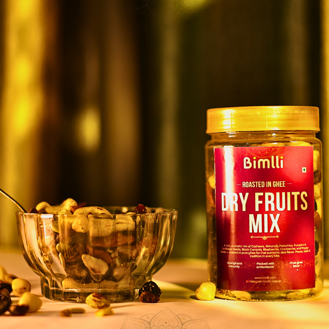 Jar of Bimlli Dry Fruits Mix with a bowl of mixed nuts on a blurred background